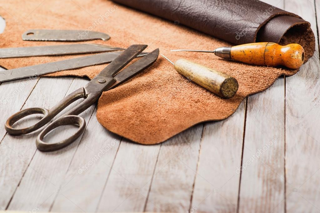 Leathersmith's work desk . Pieces of hide and leather working tools on a  work table. Stock Photo by ©Volurol 109514284